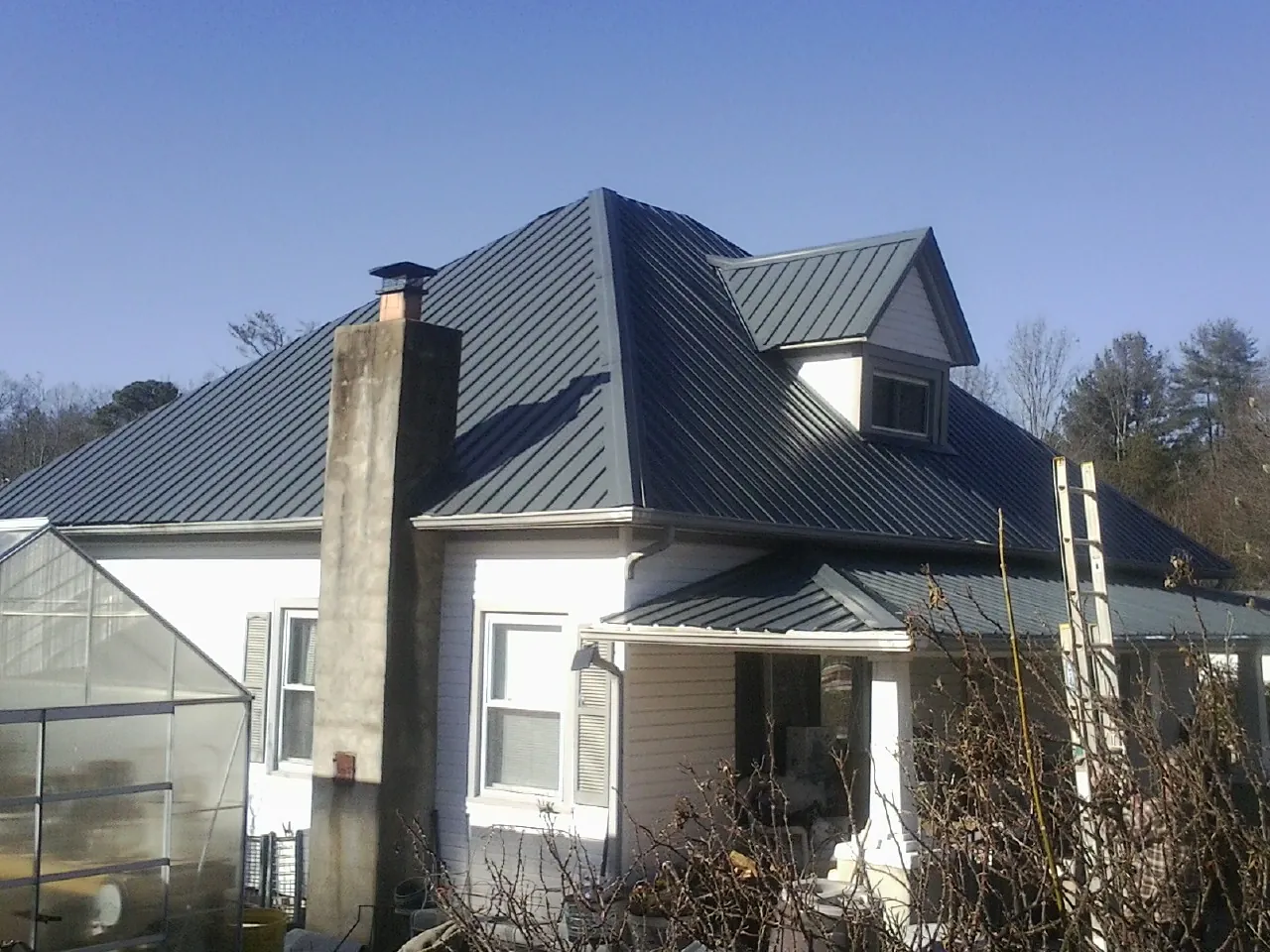 Dark blue standing seam metal roof on a white farmhouse with dormer — Slate & Tile Roof Repair by Roofing Brothers in Boyce