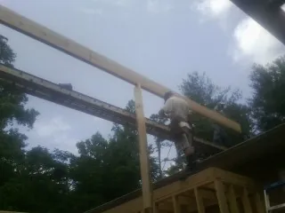 Carpenter setting a ridge beam over a new addition frame — Ice Dam Removal by Roofing Brothers in Boyce