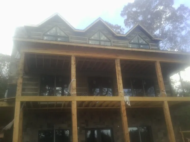 Dormers and porch framing on a large log home under construction — Roof Coating work by our crew in Boyce
