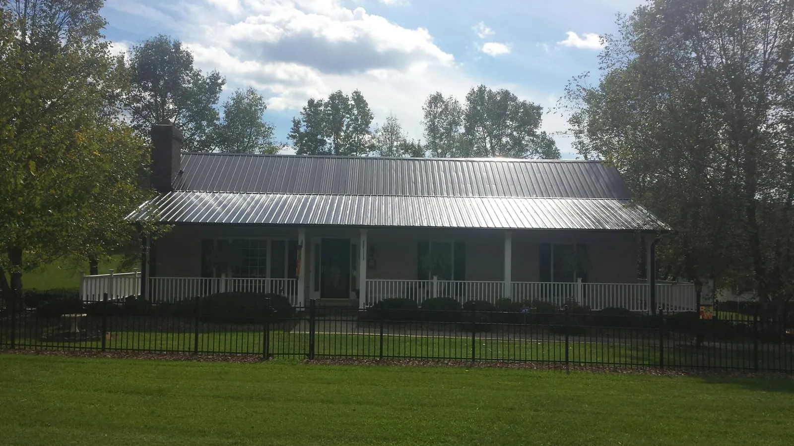 Gray metal roof on a brick ranch with a full width front porch — Gutter Guard Installation work by our crew in Boyce