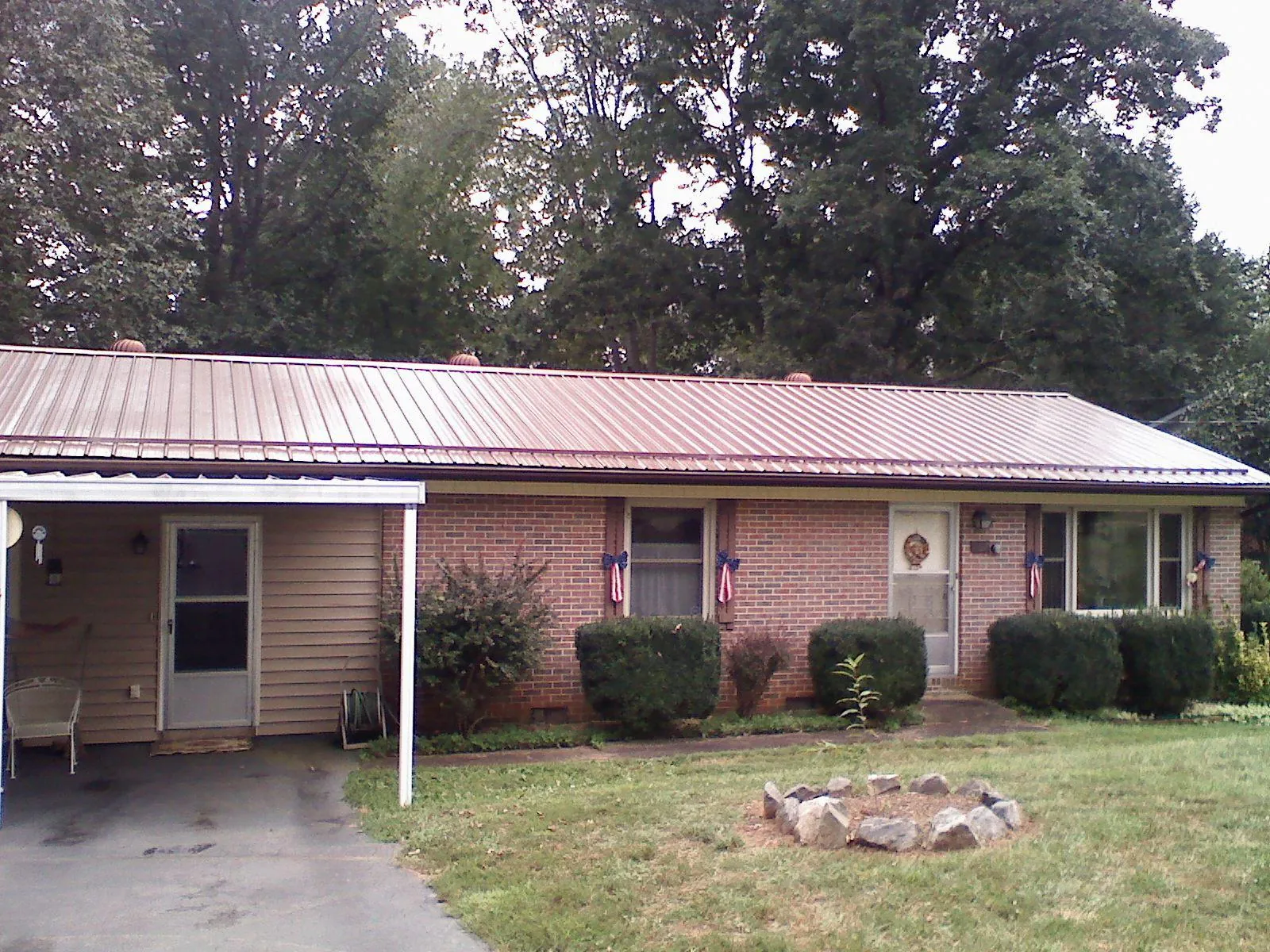 Bronze metal roof and carport on a brick ranch home — Roof Repair work by our crew in Boyce
