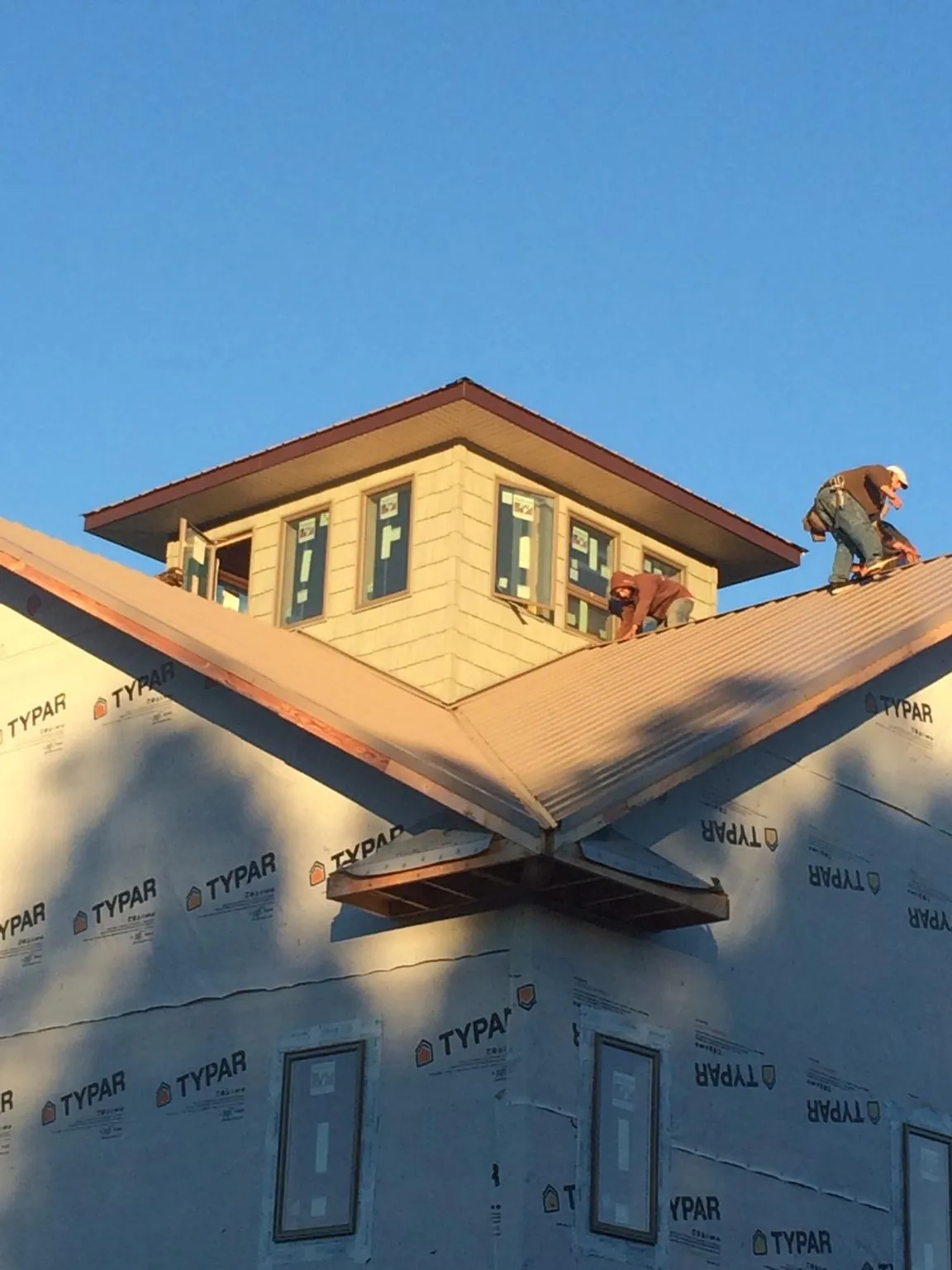 Roofers working around a rooftop cupola on a new metal roof at sunset — Roof Waterproofing in Boyce by Roofing Brothers